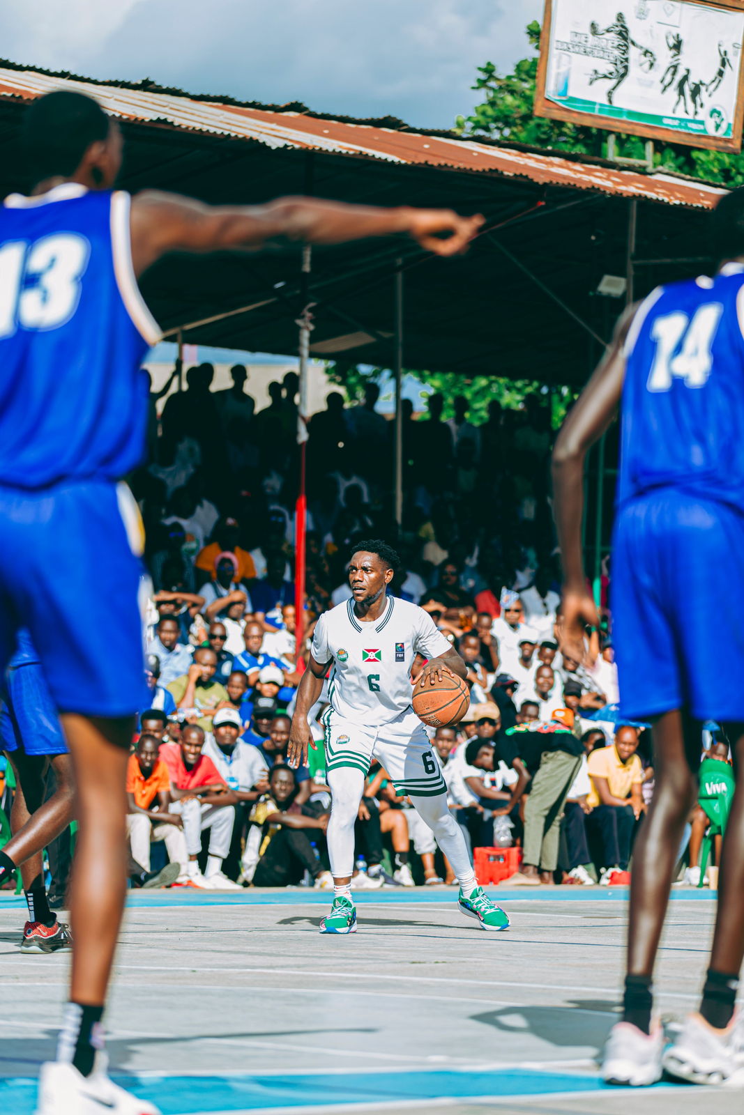 Basketball players competing on an outdoor court with spectators nearby